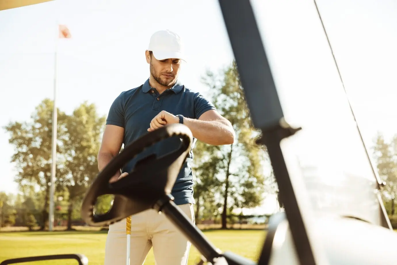 A young male golf player looking at a wristwatch