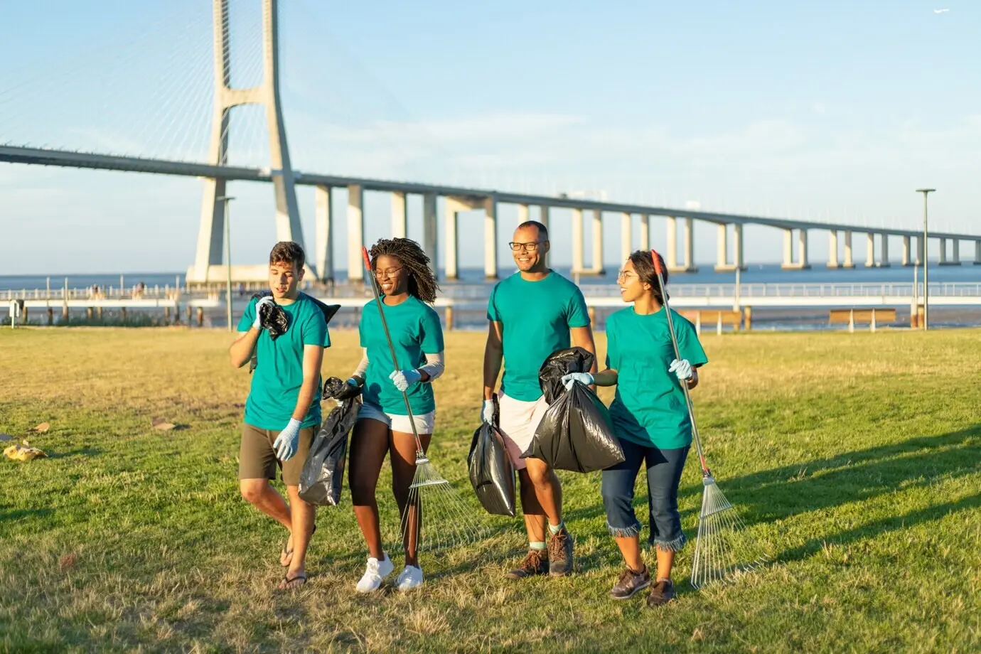 A multiracial group of volunteers carrying trash from a city lawn